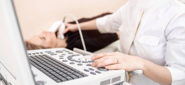 Doktor, iyot eksikliği nedeniyle klinikte kadın tiroit bezini ultrason ile muayene ediyor.