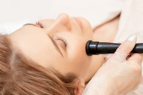 Jovem mulher recebendo RF elevação massagem facial elétrica para a pele do rosto — Fotografia de Stock