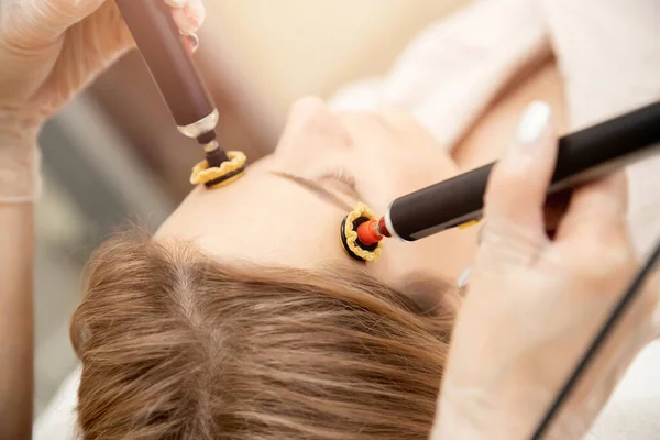 Mulher recebendo rosto pele cuidados rejuvenescimento com rf elevação aparelho elétrico salão de beleza profissional — Fotografia de Stock