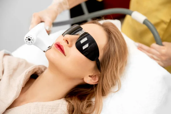 Beautiful woman face receiving laser hair removal procedure beauty salon. Concept cosmetology care skin — Stock Photo, Image