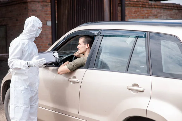 El conductor con máscara protectora Covid-19 presenta tarjetas de identificación a los médicos fronterizos entre regiones. Concepto coronavirus viaje en coche — Foto de Stock