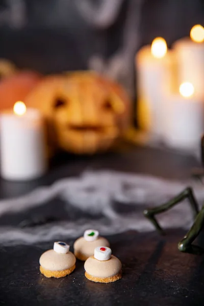 Dulces y galletas de halloween estilizadas para vacaciones sobre fondo oscuro con telarañas, calabazas y velas — Foto de Stock