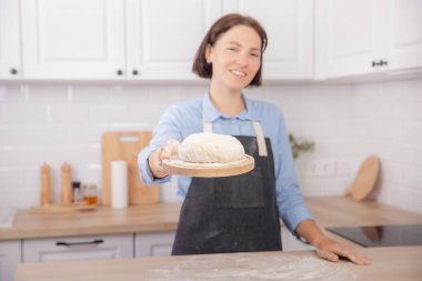 Hafif İskandinav mutfağının arka planında kadının elinde ev yapımı ekmek ve pizza yapmak için nefis havadar hamur.