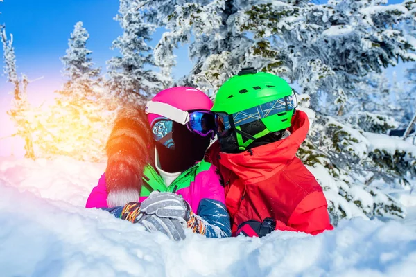 Amare coppia baci nella neve invernale, snowboarder e sciatore si trovano sullo sfondo della foresta, giornata di sole — Foto Stock