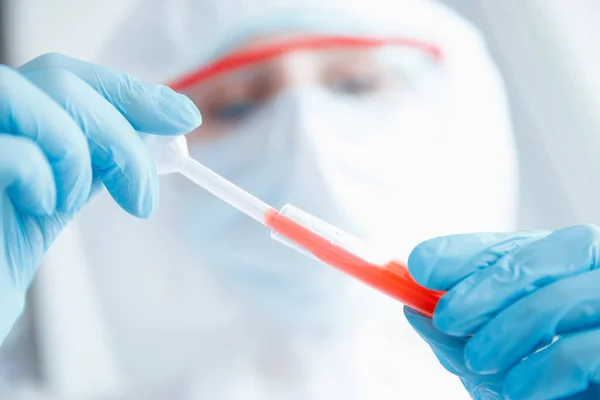 Trabalhador médico em laboratório coloca amostra de sangue para exame em analisador automático. Teste de ADN, detecção de vírus. Fundo de luz azul — Fotografia de Stock