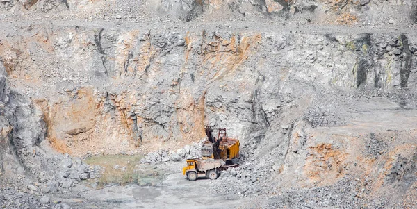 Mina a cielo abierto de piedra. Excavadora está cargando materias primas en camión amarillo para el transporte para combinar — Foto de Stock
