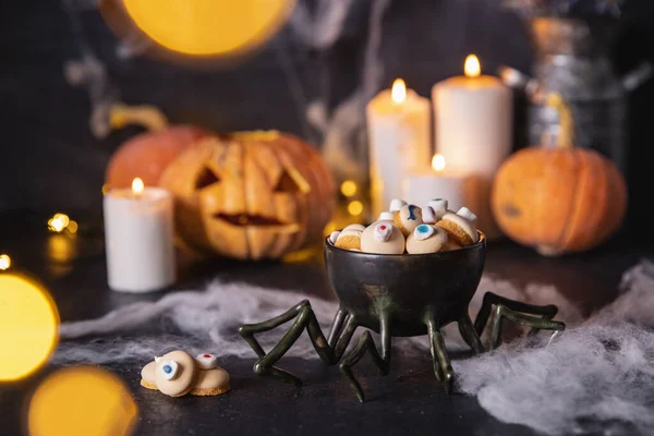 Caramelos y galletas en forma de ojo para las vacaciones de halloween, fondo oscuro con telarañas, calabazas y velas — Foto de Stock