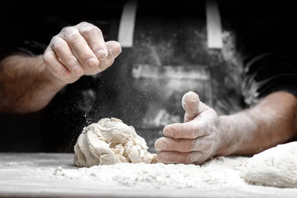 Manos de panadero macho preparando masa de levadura con polvo de harina blanca sobre fondo negro, sacar para pasta y pizza — Foto de Stock