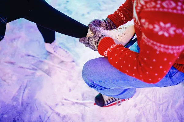 L'uomo aiuta a mettere sui pattini per la pista di pattinaggio neve alla ragazza, concetto di vacanza invernale, riposo familiare — Foto Stock