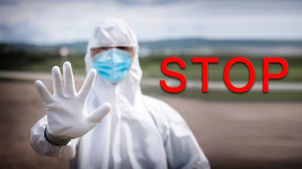 Ban movement of cars on border of cities due to pandemic coronavirus COVID 19 or Bubonic Plague, man in biological protective suit shows stop gesture — Stock Photo, Image