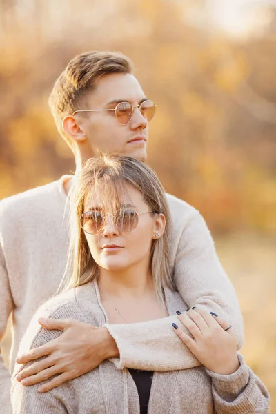 Liebendes Paar in Sonnenbrille, kuscheliger Pullover vor dem Hintergrund des Herbstparks — Stockfoto