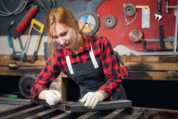 Hermosa joven ingeniera artesanal se para con delantal de regla en el fondo de herramientas artesanales. Concepto de pequeña empresa en garaje en sala industrial — Foto de Stock