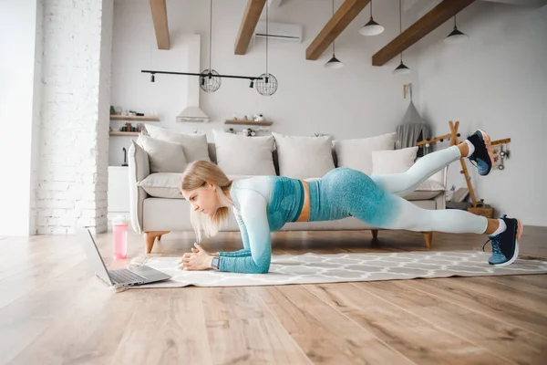 Evde online fitness çalışması, dizüstü bilgisayarda video izleyen bir kadın, internette sörf yaparken yoga eğitimi alan bir kadın. — Stok fotoğraf