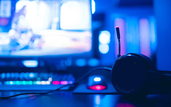 Professional cyber video gamer studio room with personal computer armchair, keyboard for stream in neon color blur background. Soft focus