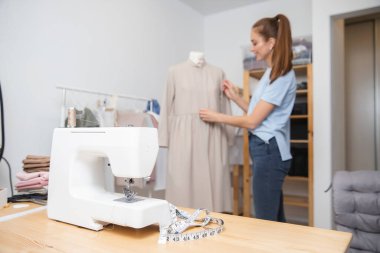 Elbise dikmek için işyeri. Terzi kadın moda tasarımcısı genç kadın mankenlerle çalışıyor, broşlar kumaşlı terziler de elbise için.