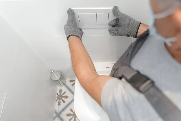 Encanador em máscara médica instalando vaso sanitário no banheiro, trabalho no banheiro — Fotografia de Stock