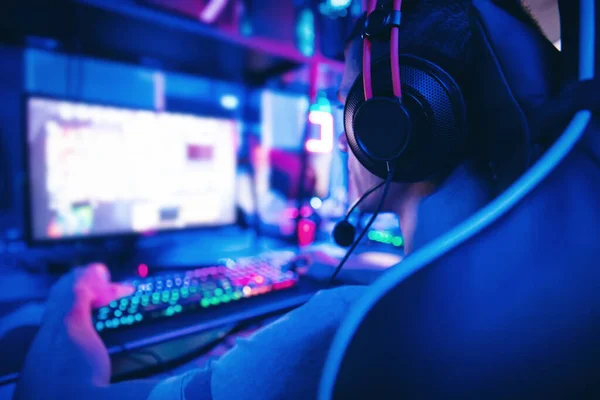 Jovem jogador jogar jogos de vídeo online com fones de ouvido no café clube de internet, cor azul. Conceito de Esports — Fotografia de Stock