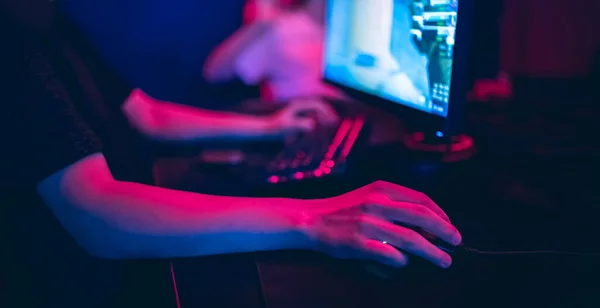 Jugador profesional jugando torneos de juegos en línea ordenador PC con auriculares, fondo rojo y azul borrosa —  Fotos de Stock