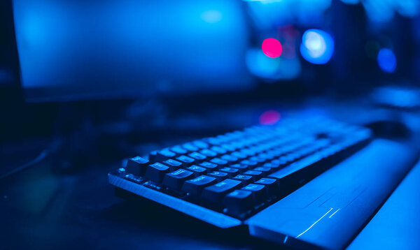 Professional cyber video gamer studio room with personal computer armchair, keyboard for stream in neon color blur background. Soft focus