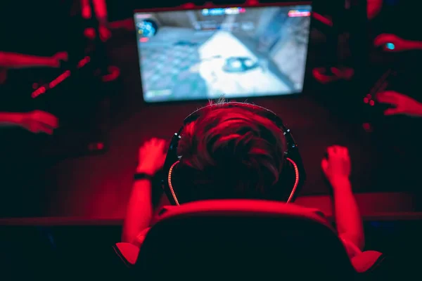 Επαγγελματίας gamer που παίζει online παιχνίδια τουρνουά PC υπολογιστή με ακουστικά, θολό κόκκινο και μπλε φόντο — Φωτογραφία Αρχείου