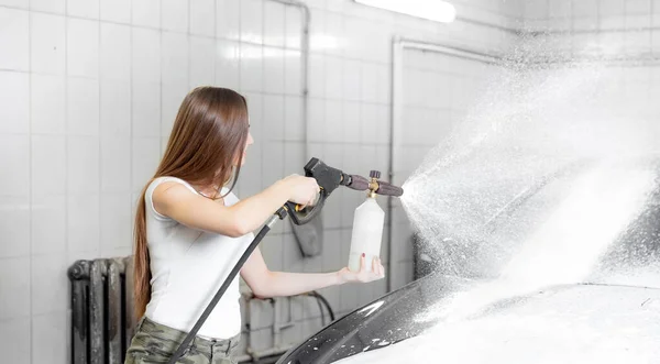 Layanan cuci mobil. Wanita pekerja membersihkan mobil menggunakan air bertekanan tinggi — Stok Foto