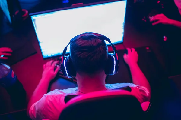 Profissional gamer saudação e apoio equipe punhos mãos jogo on-line em neon cor borrão fundo. Foco suave, visão traseira — Fotografia de Stock