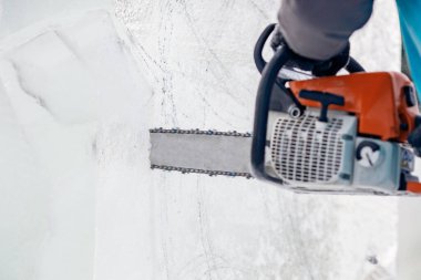 Buz heykeli oymacılığı yapan adam elektrikli testere kullanır. Donmuş kışı keser.