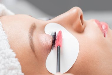 Makro kirpik uzatma prosedürü. Kadın usta tarakları kirpikleri