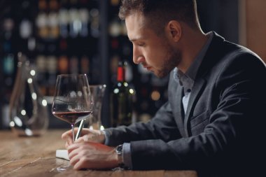 Sommelier erkekleri kırmızı şarap tatma kartı taşır.