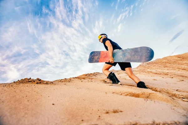 Сноубордист поднимается на вершину песчаной дюны для сноуборда — стоковое фото