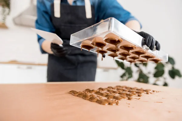 菓子の女の子は、ベルギーのチョコレートで作られたキャンディーのためのフォームを保持しています — ストック写真
