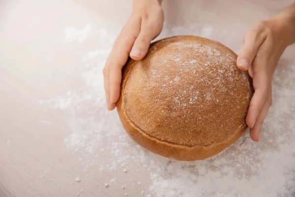 Boulanger pain rond soufflé à la main repose sur la table avec de la farine, fond de cuisine blanc — Photo