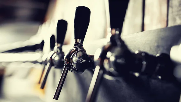 Grifos de acero artesanales de cerveza crudos en el pub. Enfoque selectivo, sol claro —  Fotos de Stock