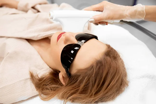 Женщина получает лазерный уход за кожей лица в салоне красоты — стоковое фото