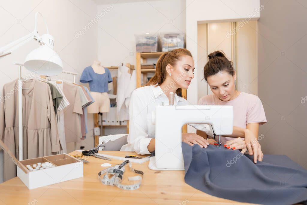 Sew working, two woman dressmaker making pattern on grey material