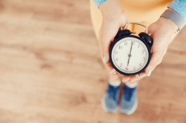 Sağlıklı uyku konsepti. Spor giysili kız sabahın altısında spor salonunun spor salonuna gitmek için alarmlı saat kullanıyor.