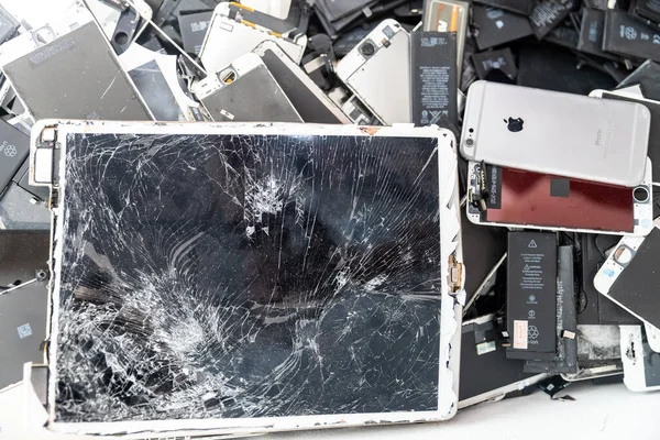 RUSIA - 27 de julio de 2020: pantallas rotas iPhone, primer plano de las baterías de teléfonos móviles usados, paneles de tabletas, ordenador portátil recogido para su eliminación en envases de plástico inmrepair y greenpeace — Foto de Stock