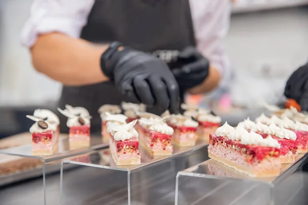Close-up of chef hands preparing cakes and desserts covered with chocolate glaze