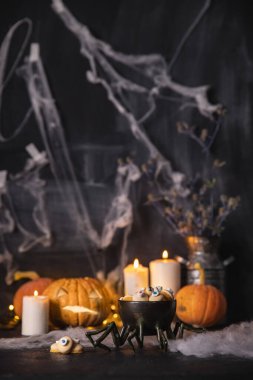 Cadılar Bayramı şekerlemeleri ve kurabiyeler. Karanlık arka planda, örümcek ağları, balkabakları ve mumlarla tatil için.