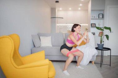 Lastik bant egzersiziyle evde antrenman yapmak. Spor elbiseli spor kadın.