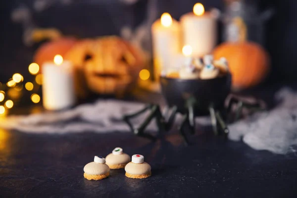 Caramelos y galletas en forma de ojo para las vacaciones de halloween, fondo oscuro con telarañas, calabazas y velas — Foto de Stock