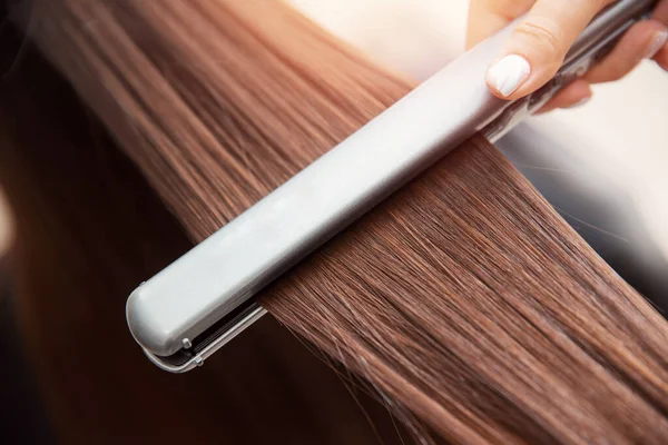 Close up hands of professional hairdresser beauty salon, straighteners curling female hair — Stock Photo, Image