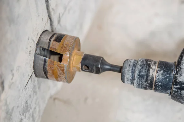 Boring hole in wall for electric outlet by power hammer drills tool
