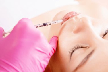 Dudakların güçlendirilmesi. Güzel genç kadın ağzı hyaluronik asit enjeksiyonu alıyor.