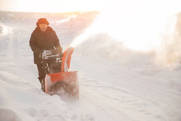 雪送り機で歩道から雪を掃除する男冬 — ストック写真