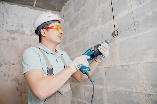 Builder man with pneumatic hammer drill perforator with diamond crown making hole in wall for electric cable, socket, switch — Stock Photo, Image