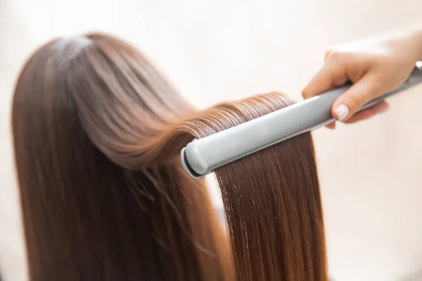 Cerca de las manos de peluquería profesional salón de belleza, alisadores rizando el cabello femenino — Foto de Stock