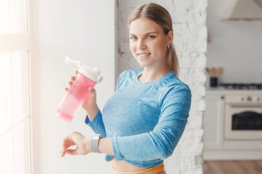Kadın suyu karıştırıcıdaki protein karışımıyla dolduruyor. Atletik kız evde antrenman yaptıktan sonra nabız ve kan oksijen seviyesini ölçer.