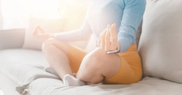 Красивая молодая кавказка, сидящая в позе йоги лотос дзен и медитирующая. Концепция расслабиться на диване гостиной дом — стоковое фото