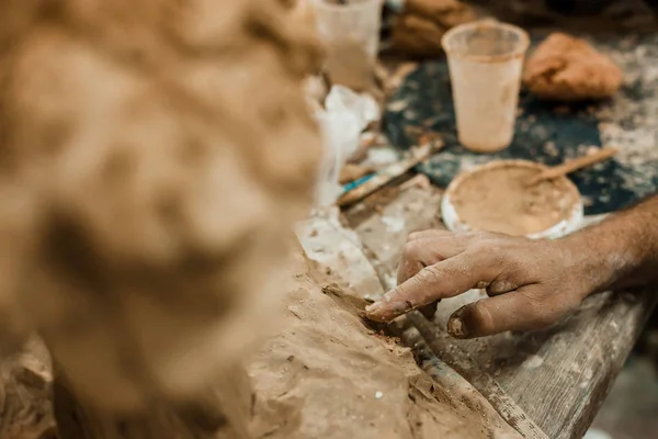 messy hands working clay, close up and focus on potters palms with pottery